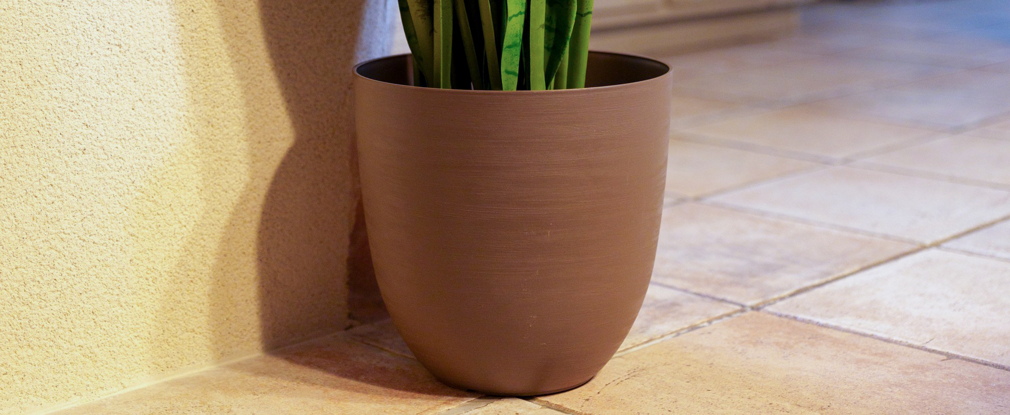Pot en plastique de couleur taupe sur du carrelage